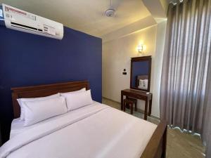 a bedroom with a white bed with a blue wall at Kandy City Inn in Kandy