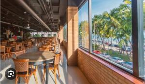 un restaurante con mesa, sillas y ventana en LUXO 710-Quarto e Sala com Varanda de frente Mar, en Maceió