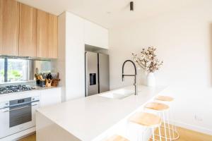 een witte keuken met witte aanrechtbladen en houten kasten bij Discover an Idyllic Boho Style Retreat in Geelong in Geelong West