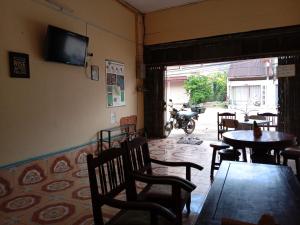 a restaurant with tables and chairs and a television on the wall at Bami thakhek hostel in Thakhek