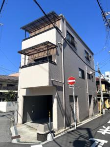 a white building with a garage on a street at Naos House Osaka 4 New Open 一軒家貸切 in Osaka