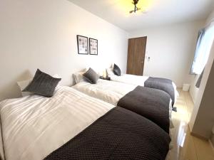 two beds in a room with white and black at Naos House Osaka 4 New Open 一軒家貸切 in Osaka +28 photos