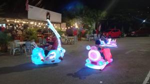 three children riding on toy cars in a parking lot at Golden Leaf Boutique Hotel Nusa Idaman Branch in Johor Bahru