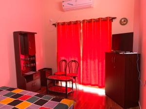 1 dormitorio con cortinas rojas, mesa y sillas en Bolpur Shantiniketan Bungalow on Kopai River en Santiniketan