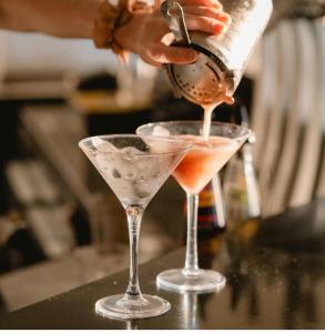 a person pouring a drink into two martini glasses at Absolute Beachfront at the Pier Glenelg in Adelaide