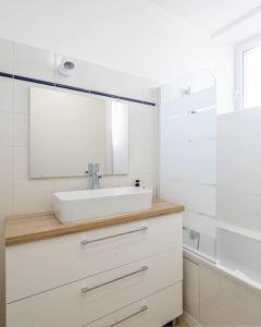 Un baño blanco con lavabo y espejo. en Le Magnifique T3, en Limoges