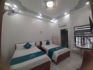 1 dormitorio con 2 camas y ventana en Nhà Nghỉ Hà My, en Quảng Ngãi