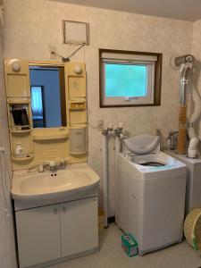 a bathroom with a sink and a toilet and a mirror at FURANO UEDA HOUSE in Furano