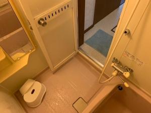 La petite salle de bains est pourvue d'une douche et d'un distributeur de papier toilette. dans l'établissement FURANO UEDA HOUSE, à Furano