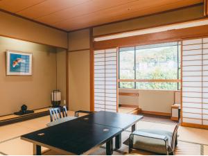 a dining room with a table and chairs and a window at Hotel Gyokusen in Matsue