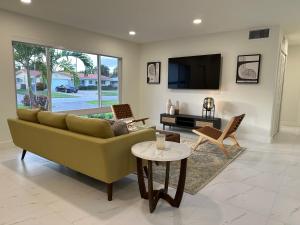 a living room with a couch and a tv at The Sun House - 3 Bed, 2 Bath, Private Pool, Fire Pit, Huge Backyard in Fort Lauderdale