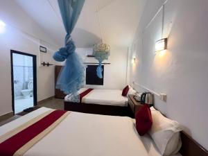 Habitación de hotel con 2 camas y baño en Ama Garden Sauraha, en Sauraha
