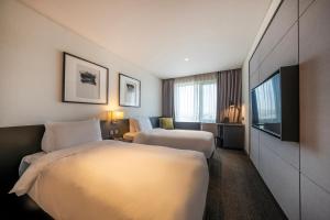 ein Hotelzimmer mit 2 Betten und einem Flachbild-TV in der Unterkunft Hotel Marinabay Seoul in Gimpo
