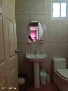 a bathroom with a sink and a mirror and a toilet at Discover the charm of this homely villa just a stone's throw from the beach in Bauang