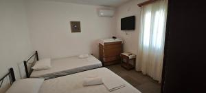 a small room with two beds and a television at ANASA in Ios Chora