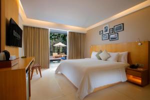 a bedroom with a large white bed and a desk at Ossotel Legian in Legian