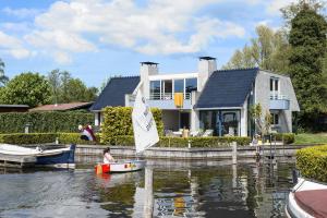 a person in a boat on the water in front of a house at Amsterdam / Loosdrecht Rien van den Broeke Village in Loosdrecht +16 photos