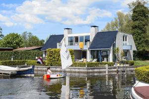 a person in a boat on the water in front of a house at Amsterdam / Loosdrecht Rien van den Broeke Village in Loosdrecht