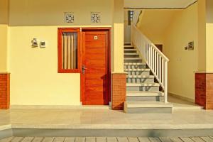 einen Flur mit Holztür und Treppe in der Unterkunft OYO 92952 Nirmala Guest House in Singaraja