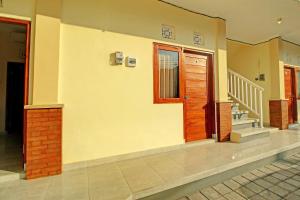 ein Haus mit einer Holztür und einer Treppe in der Unterkunft OYO 92952 Nirmala Guest House in Singaraja