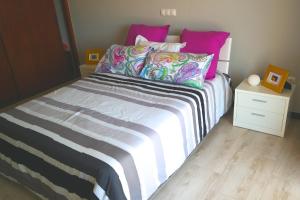 a bedroom with a bed with pink and purple pillows at Apartamento Quinta Nova in Alvor