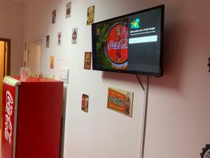 a television on a wall next to a refrigerator at Loft Coca-Cola Passo Fundo in Passo Fundo