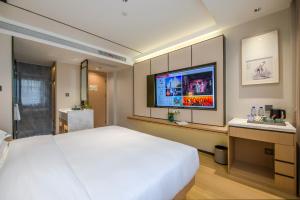 a bedroom with a large white bed and a flat screen tv at Yiwu Baide Theme Hotel in Yiwu
