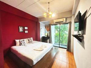 sypialnia z czerwoną ścianą z łóżkiem i oknem w obiekcie Hide Bangkok Hostel w mieście Bangkok