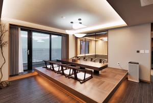 Gyeongju Denbasta Ryokan في جيونجو: غرفة مع طاولة بينج بونغ ونوافذ كبيرة