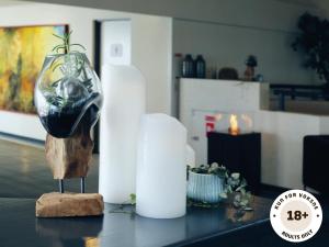 a table with white candles and a vase on it at Ærø Hotel - Adults only in Marstal