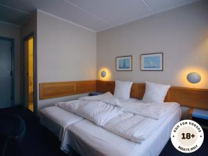 a bedroom with a large bed with white sheets at Ærø Hotel - Adults only in Marstal