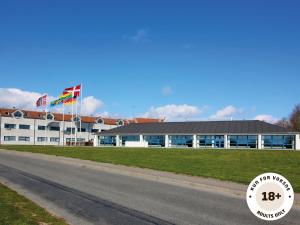 a building with two flags in front of a road at Ærø Hotel - Adults only in Marstal