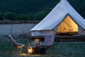 a tent with two chairs and a table with candles at Shangri -la Liotard Farm Fix Camp in Shangri-La