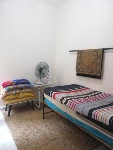 a bedroom with two beds and a table with a fan at Roomstay homestay Ahmad Rompin in Kuala Rompin