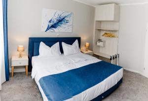 ein Schlafzimmer mit einem blauen und weißen Bett mit zwei Tischen in der Unterkunft Aneton Garni Hotel in Thale