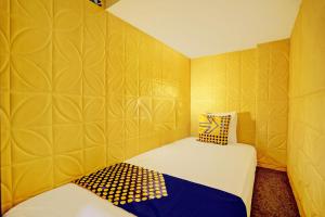 um pequeno quarto com 2 camas e uma parede amarela em SPOT ON 92980 Luxury Capsule Homestay em Sidoarjo