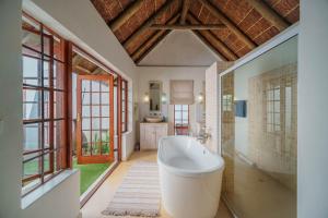 a bathroom with a tub in a room with windows at Cottage on College in St Francis Bay