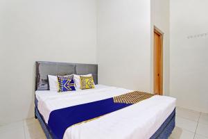 een slaapkamer met een groot bed met blauwe en gele kussens bij SPOT ON 92926 Guest House Cemara 1 Syariah in Brebes