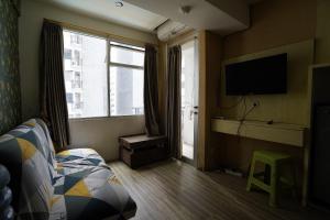 a bedroom with a bed and a tv and a window at Collection O 92981 Apartemen The Jarrdin By Gold Suites Property in Bandung