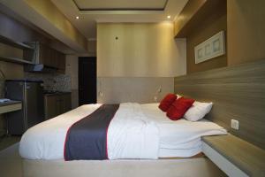 een slaapkamer met een groot bed met rode kussens bij Collection O 92981 Apartemen The Jarrdin By Gold Suites Property in Bandung