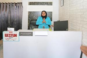 Una donna in piedi alla scrivania con le mani in alto di Capital O 92971 Pelangi Residence a Tangerang