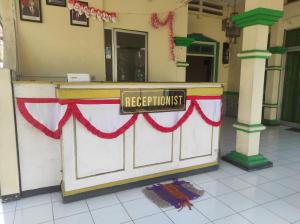 a reception desk with a red ribbon and a sign at OYO 93048 Hotel Puri Mandiri in Purworejo