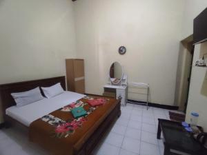 a bedroom with a bed and a mirror on the wall at OYO 93048 Hotel Puri Mandiri in Purworejo