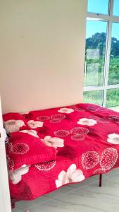 a red bed with a red blanket with flowers on it at Homestay Dena Moon Inn in Tumpat