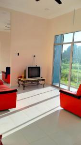 Homestay Dena Moon Inn في تومبات: غرفة معيشة بأثاث احمر وتلفزيون