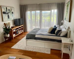 a bedroom with a bed and a large window at Callemondah Studio with stunning views, in Bangalow and Byron Hinterland in Bangalow