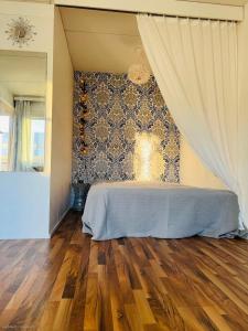 um quarto com uma cama com uma cortina e um piso de madeira em Ihana huoneisto meren lähellä. em Helsinque