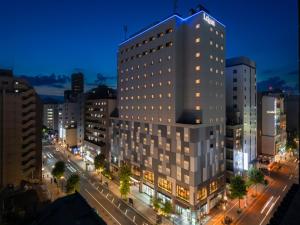 um edifício alto numa rua da cidade à noite em La'gent Stay Sapporo Odori Hokkaido em Sapporo