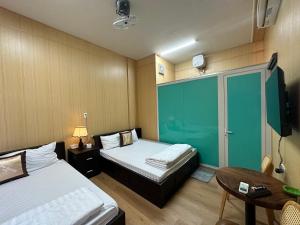 um quarto de hotel com duas camas e uma mesa e uma mesa em OYO 1199 Dung Quyen Hotel em Da Nang