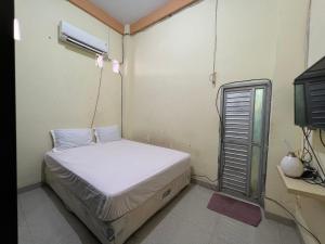 Dormitorio pequeño con cama y aire acondicionado en OYO 93053 Ziza Kost82 Syariah, 